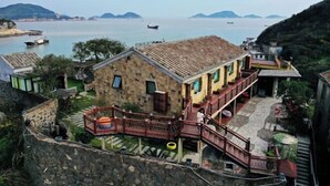 A coastal house with a stone facade, a wooden balcony, and a view of the sea. - Between sky and sea (Wenling)