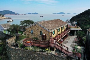 Una casa de piedra con balcón que da a un cuerpo de agua y colinas.