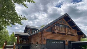 A log cabin with a balcony, a garage, and a gravel driveway. - The Southview Lodge. (Valemount)