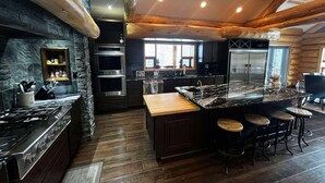 A modern kitchen with a central island, built-in ovens, and a large refrigerator. - The Southview Lodge. (Valemount)