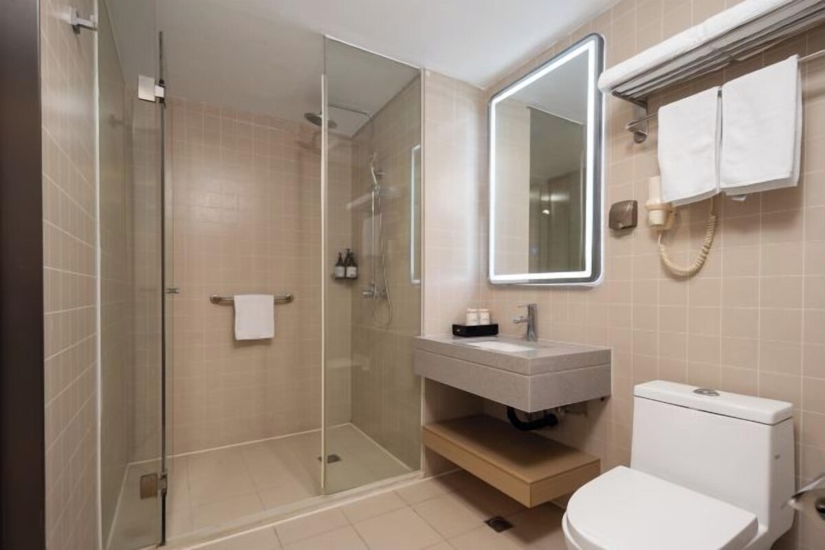 A modern bathroom with a glass-enclosed shower, a white sink, and a toilet.