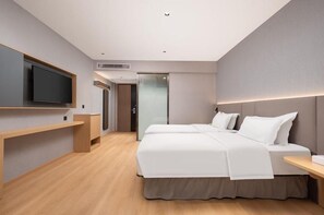 Ett modernt hotellrum med en stor säng, en tv som är monterad på väggen och ett skrivbord med en stol.