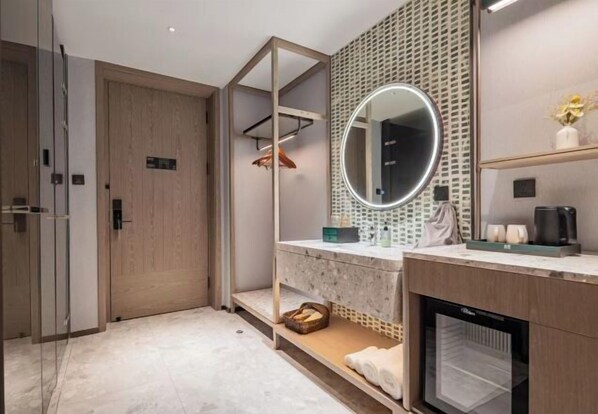 A modern bathroom with a wooden door, a glass shower enclosure, a marble vanity with a round mirror, and a coffee machine. - Jinjiang Inn Select (Hubei University of Economics Branch, Wuhan Media College Branch) (Wuhan)