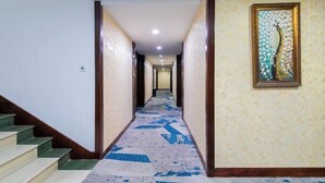 A hotel hallway with a carpeted floor, wooden doors, and a framed artwork on the wall. - Ningyuan Homestay (Zhoushan)
