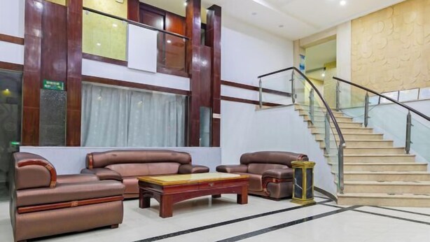 A lobby with leather sofas, a wooden coffee table, a staircase with glass railings, and a patterned wall. - Ningyuan Homestay (Zhoushan)