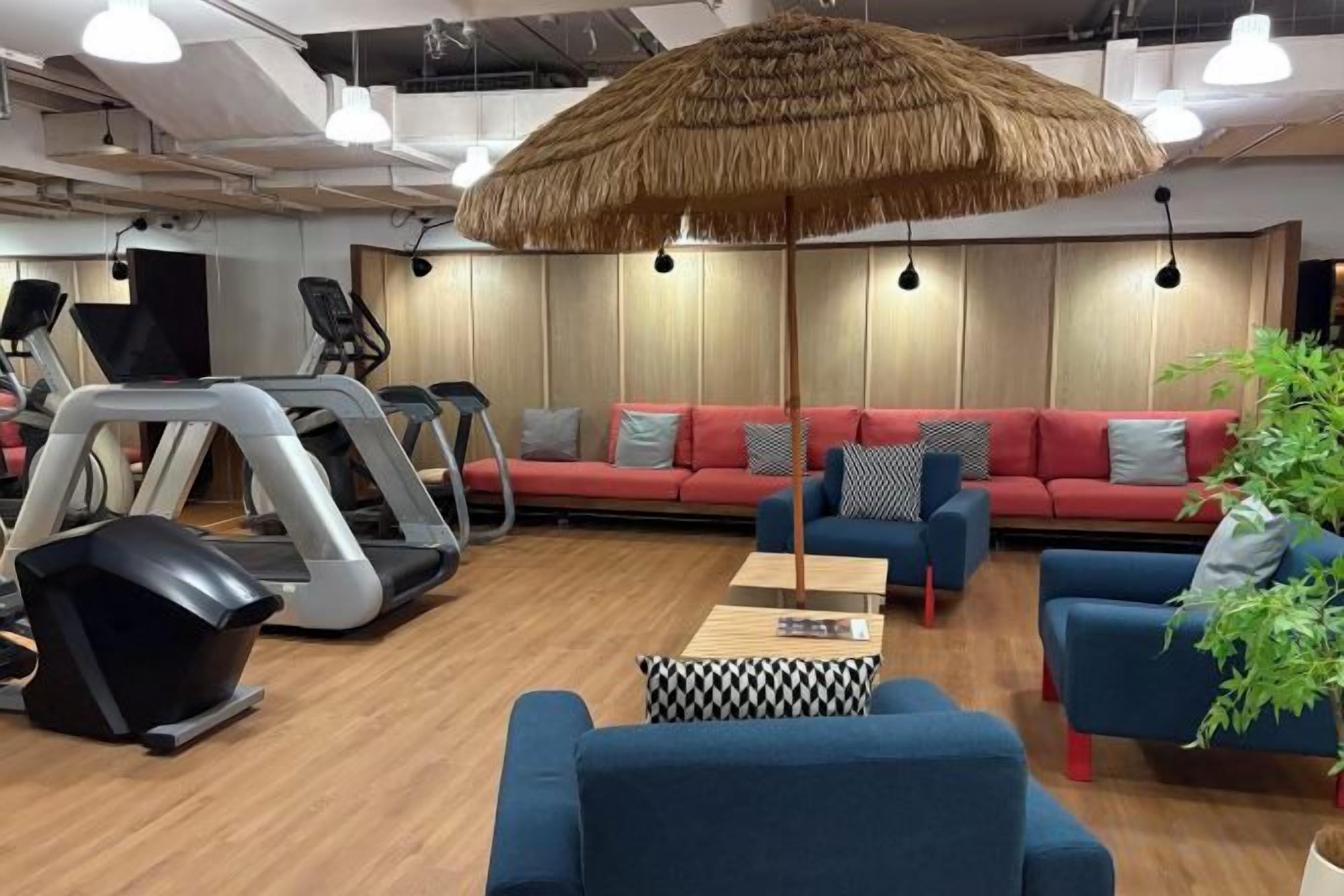 A gym with exercise equipment, a red sofa, and a large umbrella.