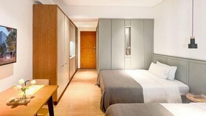Ett hotellrum med två sängar, ett skrivbord i trä, en TV och en garderob.