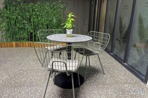 A round table with four wireframe chairs, a potted plant, and a textured floor. - baseLITE-WESTBUND Serviced Apartment (Shanghai)