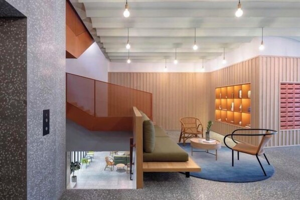 A modern interior with a staircase, seating area, and a wall with shelves. - baseLITE-WESTBUND Serviced Apartment (Shanghai)