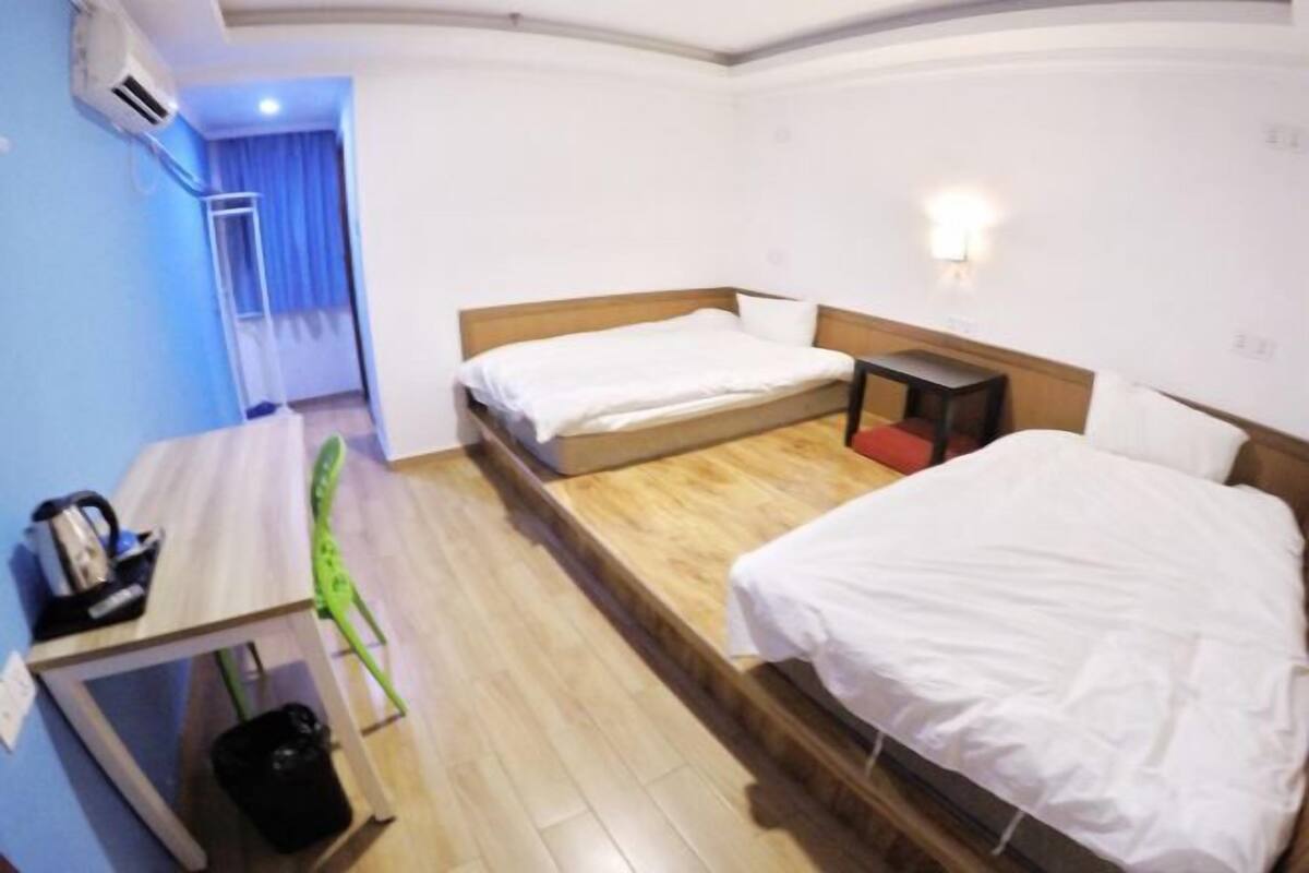 Een hotelkamer met een bed, nachtkastje en bureau met stoel.