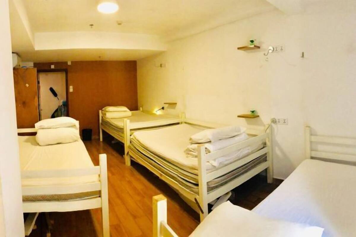 Een slaapzaal met stapelbedden, een houten vloer en een deur op de achtergrond.