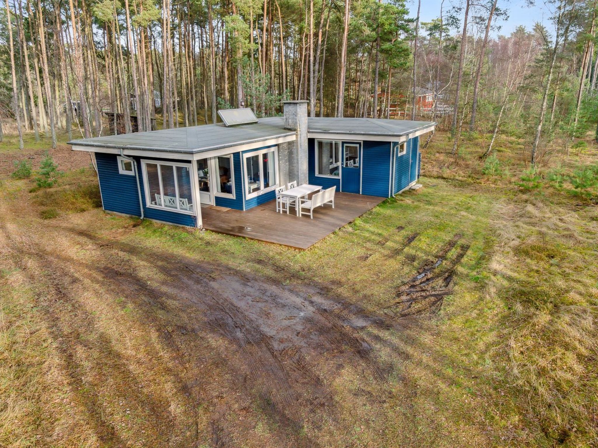 Ein modernes, zweistöckiges Haus mit Terrasse, umgeben von einem Wald.