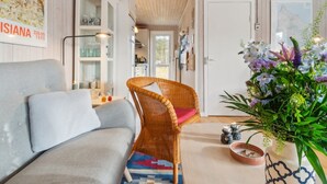 Un salón acogedor con un sofá gris, una silla de mimbre y un arreglo floral.