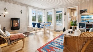 Una sala acogedora con chimenea, sillas azules, un sofá de mimbre y un televisor.