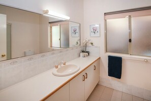 Un baño con un lavabo blanco, armarios de madera, un espejo y una toalla azul.