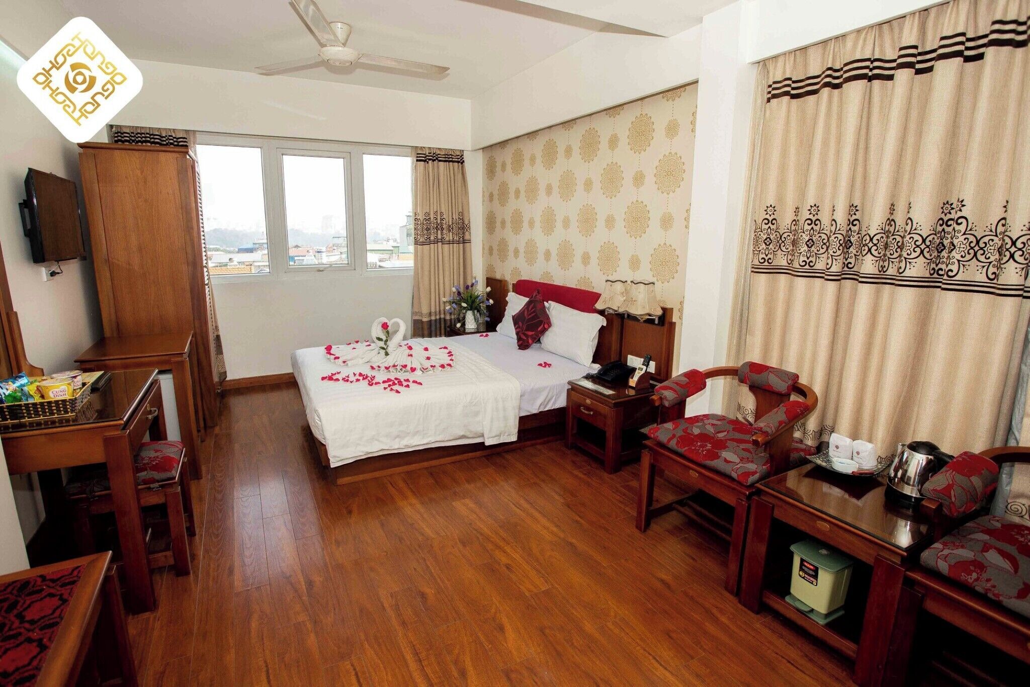 Habitación de hotel con cama, muebles de madera, escritorio y vistas a la ciudad.