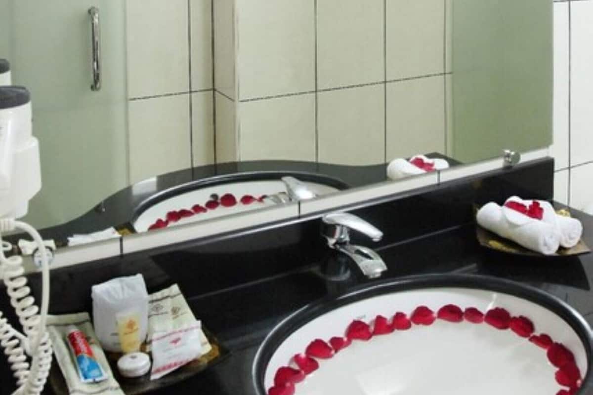 Un bany amb un lavabo blanc, un mirall, una barra de tovalloles i productes de tocador a la superfície.