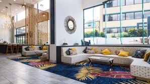 Un intérieur moderne comprenant un coin salon, un espace repas et de grandes fenêtres donnant sur les bâtiments environnants.