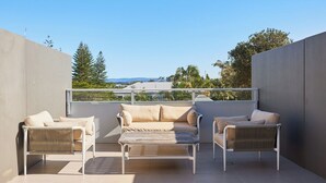 Une terrasse sur le toit, aménagée avec un ensemble de canapés et deux fauteuils, offrant une vue sur le paysage urbain et la verdure.