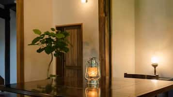 A wooden dining table with a glass top, a potted plant, and a lit lantern.