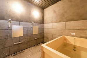 A bathroom with a bathtub, two showerheads, and a tiled wall. - Tsuzuya Village, a guesthouse with a full-fledged private sauna (Minokamo)