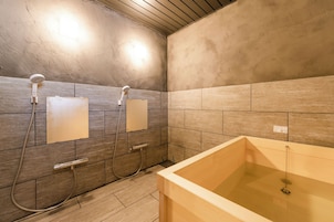 A bathroom with a bathtub, two showerheads, and a tiled wall.