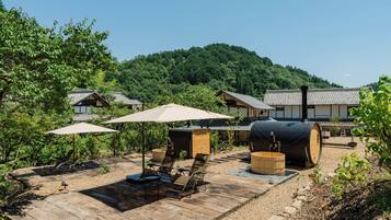 Un ryokan japonés tradicional con suelo de estequilla, muebles de madera y vistas a una colina arbolada.