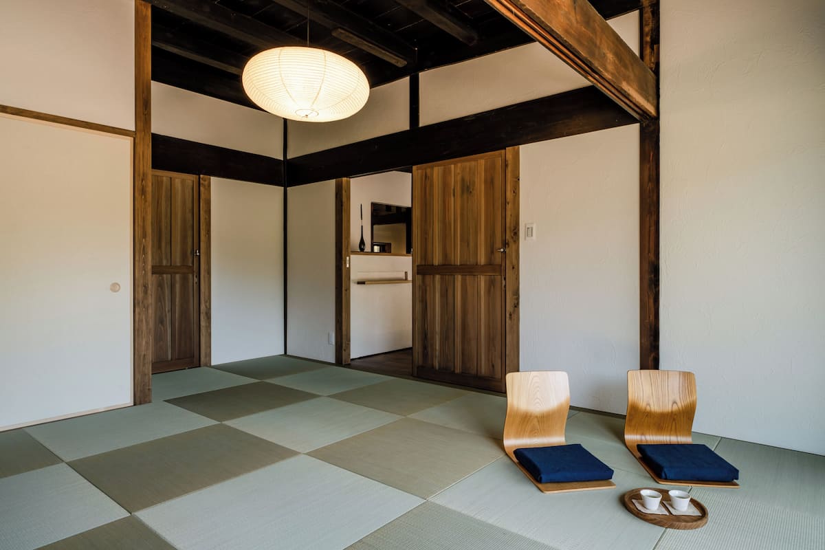 Um quarto japonês tradicional com tatames, portas deslizantes de madeira e um lanterna de papel suspensa.