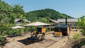A traditional Japanese ryokan with tatami mat flooring, wooden furniture, and a view of a forested hill. - Tsuzuya Village, a guesthouse with a full-fledged private sauna (Minokamo)