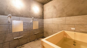 A bathroom with a bathtub, two showerheads, and a tiled wall.