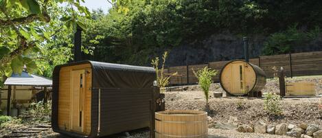 A rustic outdoor setting with wooden structures, including a covered seating area and a hot tub.