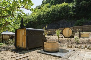 A rustic outdoor setting with wooden structures, including a covered seating area and a hot tub.