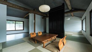 A traditional Japanese room with tatami flooring, a wooden table, and chairs. - Tsuzuya Village, a guesthouse with a full-fledged private sauna (Minokamo)