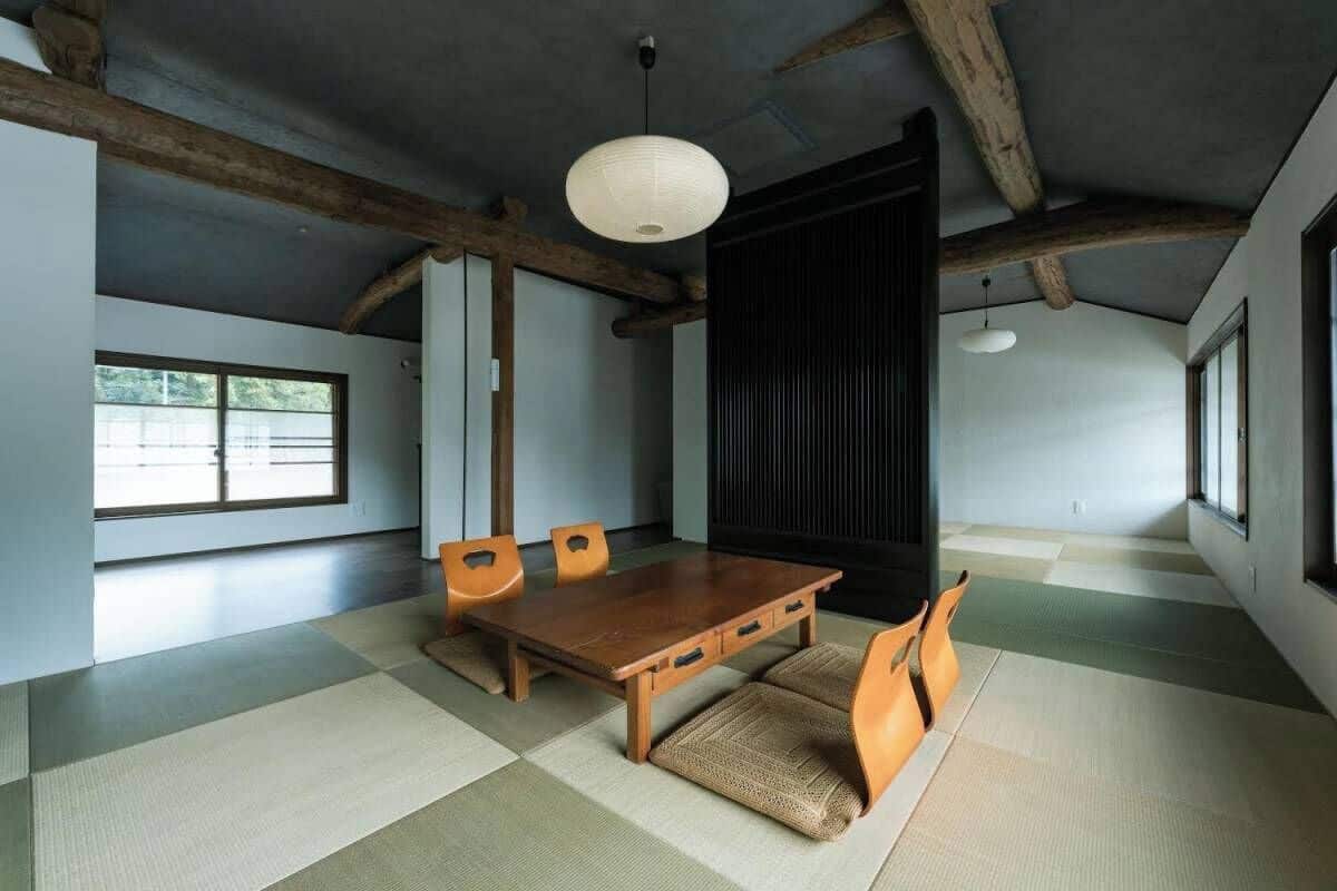 Um quarto japonês tradicional com tatames, uma mesa de madeira e cadeiras.