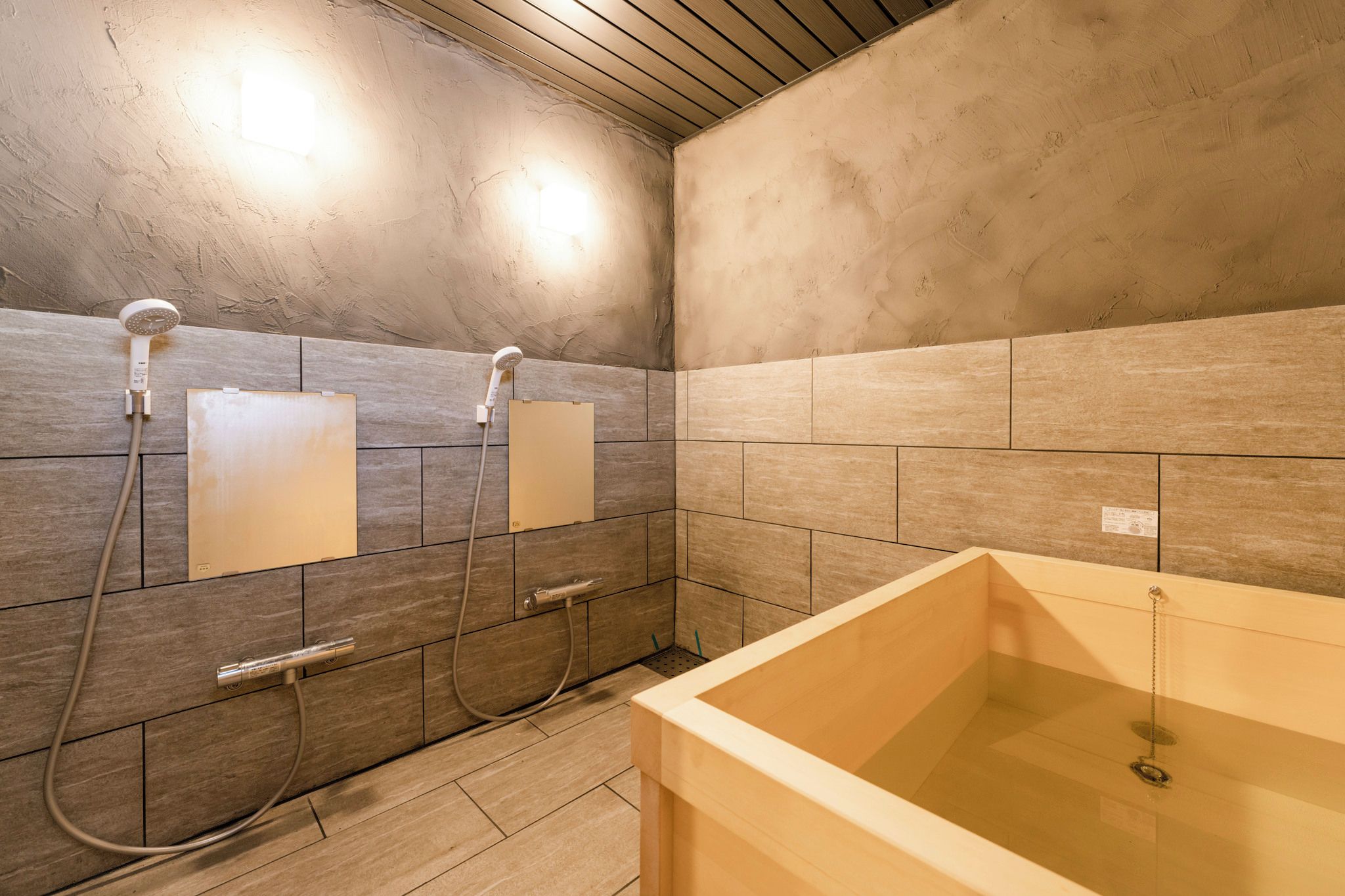 Un baño con bañera, dos cabezales de ducha y un revestimiento de azulejos.