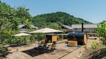 A traditional Japanese ryokan with tatami mat flooring, wooden furniture, and a view of a forested hill.