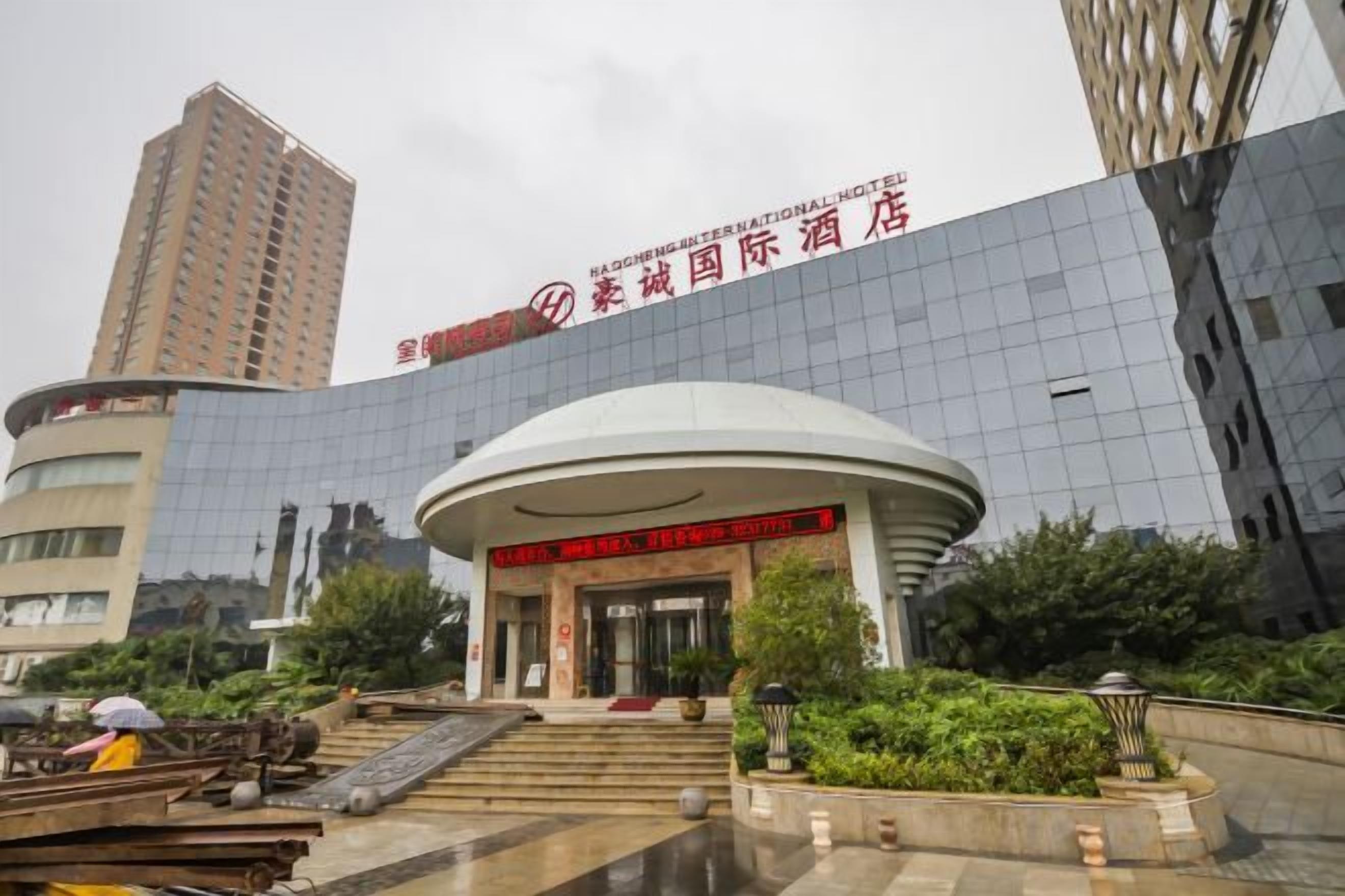 A modern hotel with a curved entrance, a large glass facade, and a prominent sign.