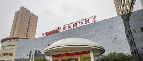 A modern hotel with a curved entrance, a large glass facade, and a prominent sign.