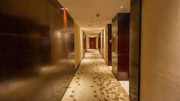A long, narrow hallway with a patterned carpet and modern lighting fixtures.