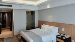 A hotel room with a bed, bedside table, and a door leading to a hallway. - Haocheng International Hotel (Sanyuan)