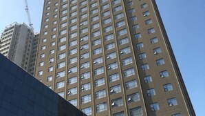 A tall, modern high-rise building with a grid of windows and a visible construction crane in the background. - Haocheng International Hotel (Sanyuan)