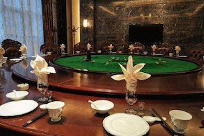 A billiards table surrounded by chairs, a green felt surface, and a dark stone wall. - Haocheng International Hotel (Sanyuan)