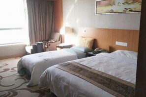A hotel room with two beds, a desk, a chair, a lamp, and a window with curtains. - Haocheng International Hotel (Sanyuan)