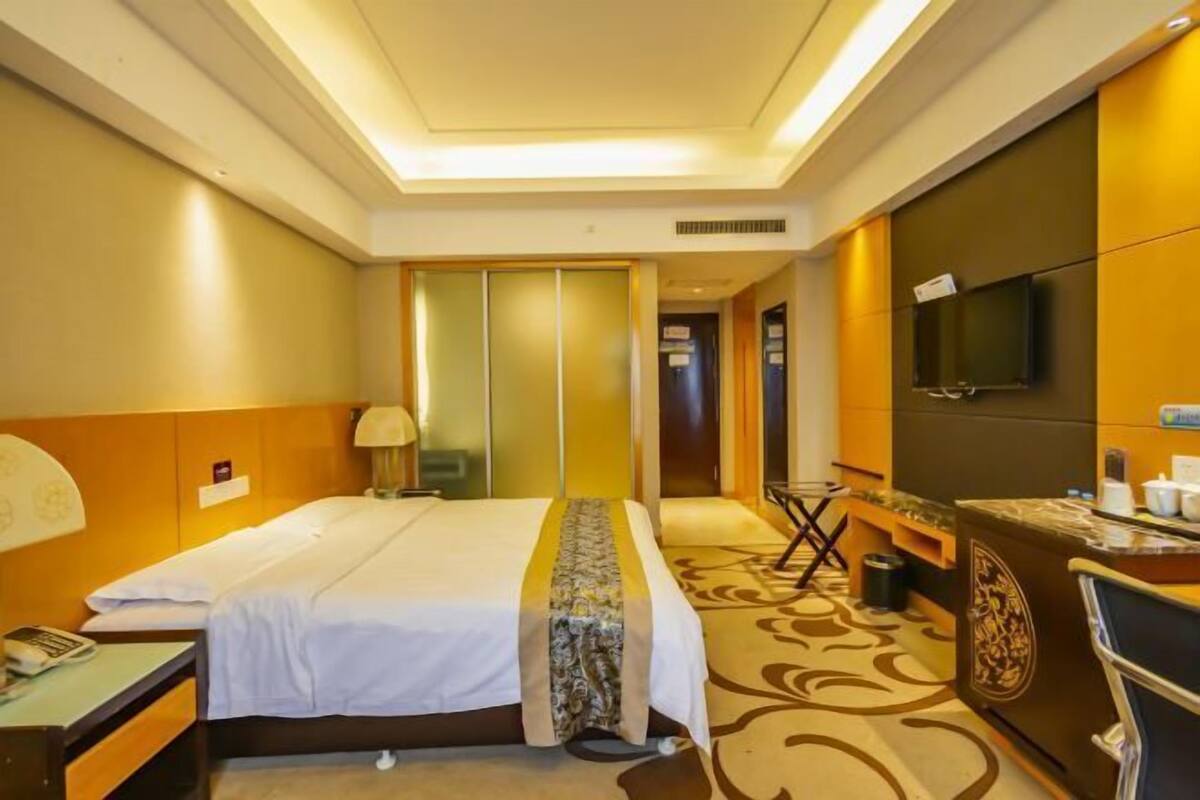 Een hotelkamer met een bed, bureau, stoel, televisie en een deur naar de badkamer.