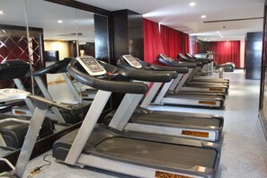 A row of treadmills in a gym with a mirrored wall and red curtains in the background. - Haocheng International Hotel (Sanyuan)