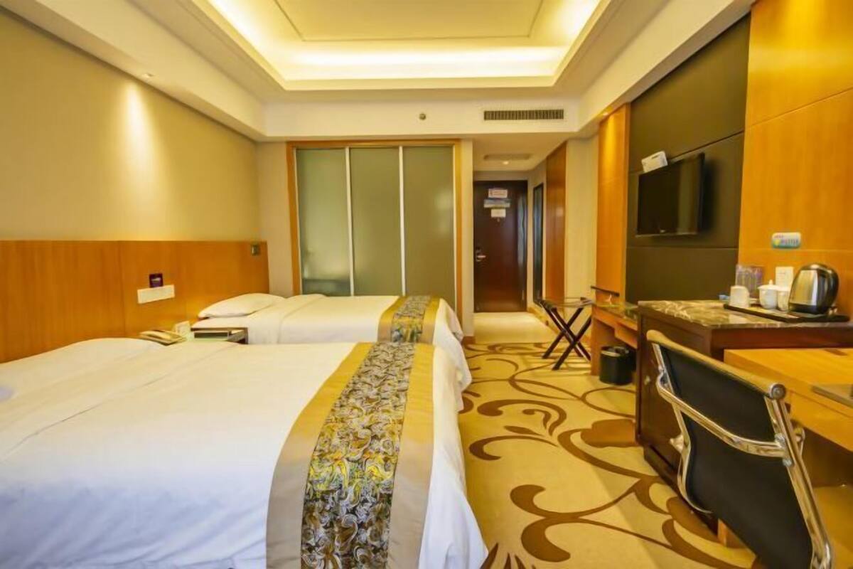 Een hotelkamer met twee bedden, een bureau, een stoel, een televisie en een badkamer.