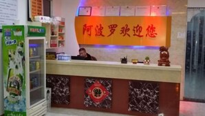 A hotel reception desk with a sign in a foreign language, a counter with a digital display, and a decorative emblem on the wall. - Apollo Hotel, South Guizhou (Yinan)