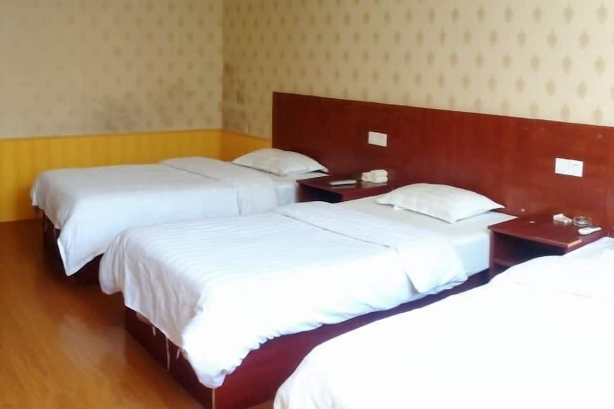 Une chambre d’hôtel avec deux lits simples, des têtes de lit en bois et une petite table de chevet avec une lampe.