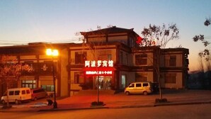 A building with a red sign, parked cars, and a streetlight. - Apollo Hotel, South Guizhou (Yinan)