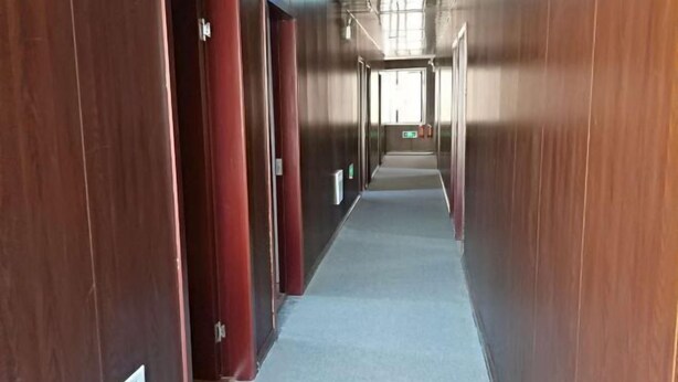 A long, narrow hallway with wooden walls and a carpeted floor, leading to a door at the end. - Haiyan Guyun Inn (Haiyan)